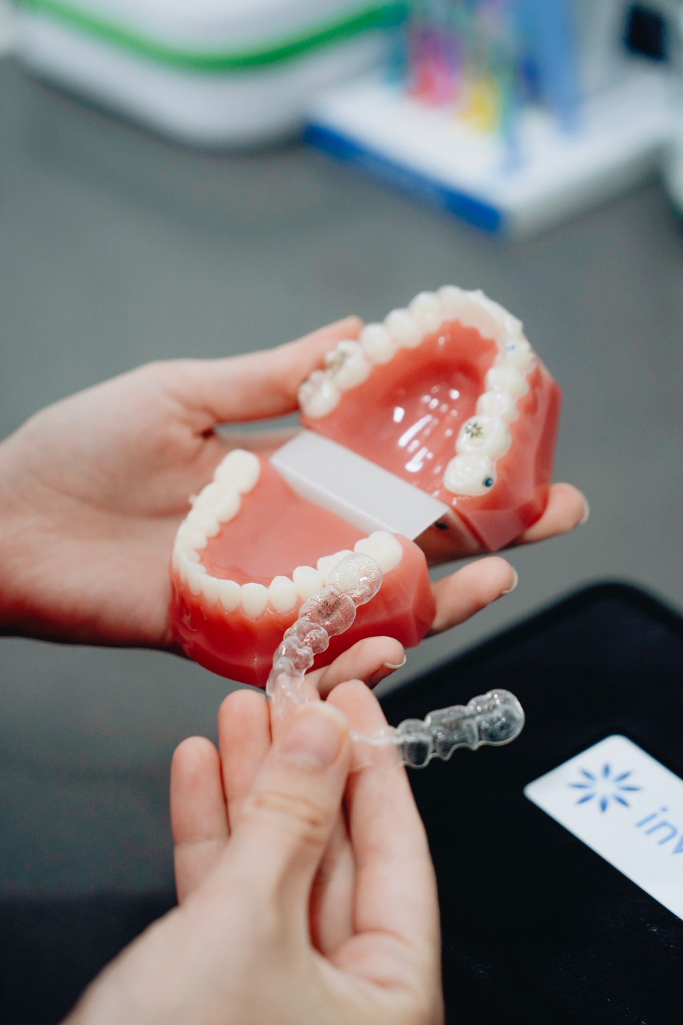 Gloved hands holding a dental cast alongside a clear aligner
